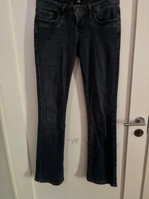 Mörkblå bootcut jeans från LTB - Snygga mörkblå bootcut jeans från LTB med klassisk femficksmodell och subtila slitningar. Jeansen har normal midja och raka ben som går ut lite nedtill. Perfekta till sneakers eller boots för en avslappnad look. Storlek: 26/32