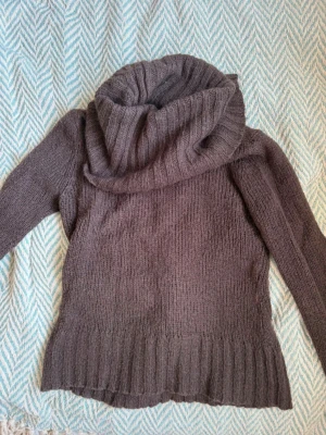 Brun stickad cute sweater - Mysig brun stickad tröja med bred polokrage och långa ärmar. Tröjan har ribbstickade muddar vid ärmslut och nederkant samt en lös passform. Perfekt för kalla dagar och enkel att styla med jeans eller kjol.