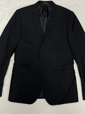 Bläck svart kavaj, storlek 46 - Fint skick! - Svart kavaj med tre knappar fram och fyra knappar på varje ärmslut. Kavajen har en innerficka och en bröstficka samt två fickor fram.  Storlek 46 Hyperion Blazer  I väldigt fint skick