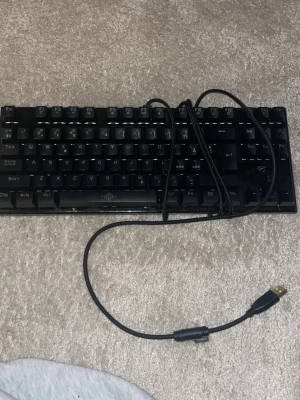 RGB mekaniskt tangentbord Havit - Säljer ett kompakt svart mekaniskt tangentbord från Havit med RGB-belysning. Tangentbordet har USB-anslutning och tydliga, upphöjda tangenter. Perfekt för gaming eller skrivande med snygg ljuseffekt i flera färger.