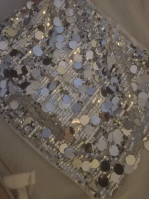 Silver glittrig paljettkjol - Snygg kort kjol täckt av stora och små silvriga paljetter som ger en riktigt glittrig look. .