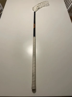 Innebandyklubba Oxdog svart/vit - Säljer en innebandyklubba från Oxdog med svart skaft, vita detaljer och vit plastblad. Greppet är lindat med vit linda och bladet är inte in nå bra skick. Perfekt för dig som gillar innebandy. Skaftet har lite repet men inget som gör något, funkar fortfarande som vanligt. 92 cm lång