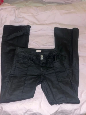 Svarta bootcut skinnaktiga jeans med låg midja - Säljer ett par svarta bootcut jeans med låg midja och dubbla knappar fram ifrån nelly. Om du är kring 165cm eller kortare och vill att de ska hå ända ner till marken så är de nog bra längd (själv är jag 171cm). Innebenslängden är 180 och midjemåttet rakt över är 36. Säljer pga att de aldrig kommer till användning och lite för små i midjan samt i längden. Skriv gärna för fler bilder eller andra frågor💞