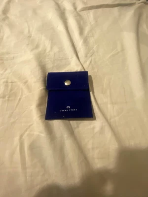 Kedjearmband i silver Urban Story - Snyggt kedjearmband i silverfärgat metall från Urban Story. Armbandet har en chunky design med breda länkar och kommer med en blå sammetsförpackning med tryckknapp. Perfekt accessoar för att lyfta din stil.