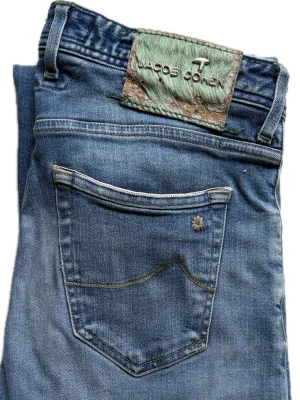 Limited Edition Jacob Cohën Jeans | W32 - Snygga blå jeans från Jacob Cohen i modellen 622, limited edition. Klassisk femficksdesign och raka ben. Jeansen har en diskret slitning framtill och en unik patch baktill i grönt och brunt. Tillverkade i mjukt denimtyg för en bekväm känsla.