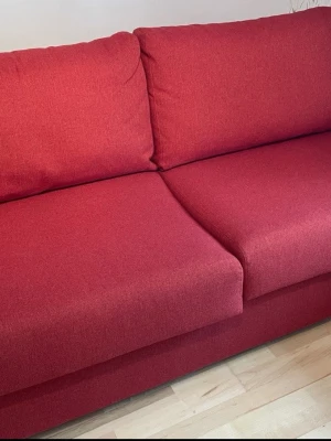 Röd soffa från Hovden - Röd soffa från Hovden med två stora sittdynor och ryggkuddar. Klädseln är i ett grovt vävt tyg som ger en modern känsla. Soffan har en rak och stilren form, perfekt för vardagsrummet.