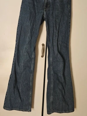 Blå bootcut jeans med utsvängda ben - Säljer ett par klassiska blå bootcut jeans med utsvängda ben och normal midja. De har mycket minimal slitage vid midjan och vida en av fickorna, annars helt felfria. De har ingen heelbite, trots att benen är full length