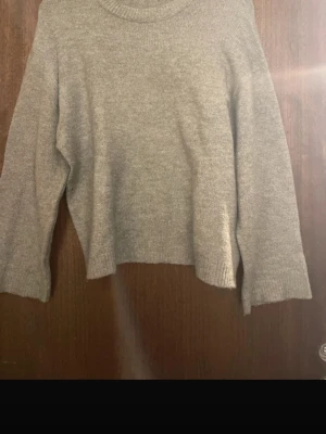 Grön stickad tröja med rund hals - Mysig grön stickad tröja med rund hals och långa ärmar. Tröjan har en rak passform och ribbade muddar vid ärmslut och nederkant. Perfekt för kyliga dagar och enkel att matcha med olika outfits.