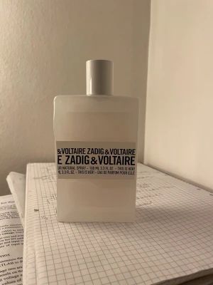 Zadig & Voltaire This Is Her! EdP 100ml - Parfymflaska i matt vit glas från Zadig & Voltaire, modellen 'This Is Her!'. Flaskan rymmer 100 ml och har en minimalistisk, fyrkantig design med svart text på etiketten. En Eau de Parfum med modern och stilren look. Finns cirka 90% kvar i flaskan.