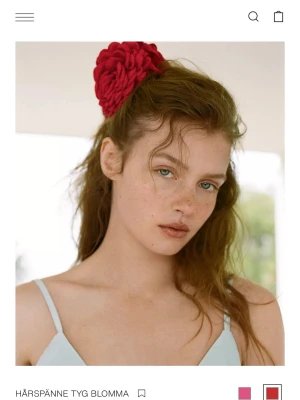 Rött hårspänne i tygblomma - Snyggt hårspänne i form av en stor röd tygblomma. Blomman har flera lager av mjukt tyg som ger en fyllig och cool look. Perfekt accessoar för att piffa upp frisyren och ge en färgklick till din stil.