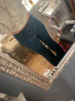 Mörkblå slim fit jeans - Snygga mörkblå slim fit jeans med klassisk femficksdesign och dragkedjegylf. Jeansen har slitningar och tvättade detaljer för en trendig look. Perfekta för dig som gillar en smalare passform och vill ha ett par stilrena jeans i garderoben.