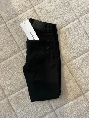 HELT NYA Dondup jeans  - Snygga svarta jeans från Dondup med klassisk femficksdesign och diskreta sömmar. Jeansen har en stilren look och är tillverkade i ett mjukt denimtyg. Perfekta för dig som gillar italiensk design och vill ha ett par riktigt schyssta jeans.