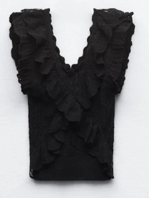 Svart Zara Volang Topp - Säljer en svart croppad topp med djup v-ringning och volangdetaljer framtill och på axlarna. Toppen är ärmlös och har en feminin, trendig look som passar perfekt till jeans eller kjol. 