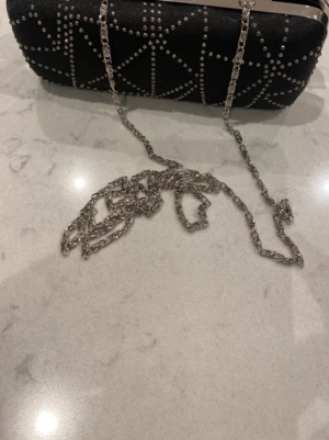 Brun axelväska i läder med tofs - Säljer en snygg brun axelväska i mjukt läder med rundad form och dekorativ tofs framtill. Väskan har justerbar axelrem och detaljer i guld. Perfekt för dig som vill ha en stilren och praktisk väska till vardagen.