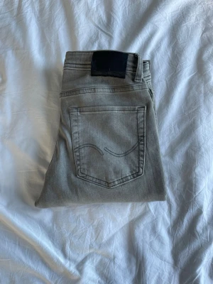 Jack and Jones jeans - Snygga grå jeans från Weekday med rak passform och klassisk femficksdesign. Jeansen har en diskret tvättad look och är tillverkade i bomull med lite stretch för extra komfort. Perfekta till en avslappnad stil och lätta att matcha med olika outfits.