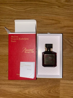 Baccarat Rouge 540 Extrait de Parfum 70ml - Lyxig parfym från Maison Francis Kurkdjian, Baccarat Rouge 540 Extrait de Parfum. Flaskan är elegant i rött glas med gulddetaljer och matchande röd ask med guldfärgad text. Innehåller 70 ml. Perfekt för dig som vill ha en exklusiv och unik doft.
