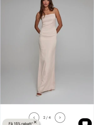 Satinklänning från Nelly  - Elegant lång klänning i ljusbeige med smala axelband och rak halsringning. Klänningen har en figurnära passform och öppen rygg, vilket ger en stilren och modern look. Perfekt för dig som gillar minimalistisk stil. Ord pris 799kr, Använd 1 gång därav inga difekter.