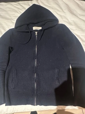 Mörkblå cashmere hoodie Sayless - Mysig mörkblå hoodie från Sayless i mjuk cashmere. Tröjan har dragkedja framtill, två fickor och en stor huva med dragsko. Perfekt för dig som gillar stilrena och bekväma plagg med exklusiv känsla.