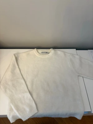 Vit stickad tröja från lager 157 - Klassisk vit stickad tröja från lager 157 med rund halsringning och långa ärmar. Tröjan har en enkel och stilren design, perfekt för lager på lager. Tillverkad i mjukt material som känns skönt mot huden.