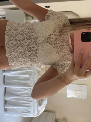 Vit spetsblus från Gina Tricot - Säljer en söt vit spetsblus från Gina Tricot. Toppen har korta ärmar, är lätt genomskinlig och har ett blommigt spetsmönster. Perfekt att styla med jeans eller kjol för en trendig look. Superfin och feminin vibe!