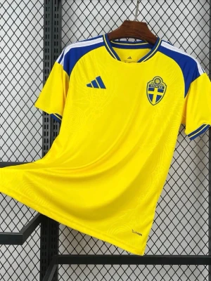 Sverige matchtröja VM 2026 - Gul matchtröja från Adidas med blå detaljer och Sveriges landslagsemblem på bröstet. Tröjan har korta ärmar, rund hals och blå-vita inslag på axlarna. Tillverkad i lätt och ventilerande funktionsmaterial, perfekt för fotboll eller träning.