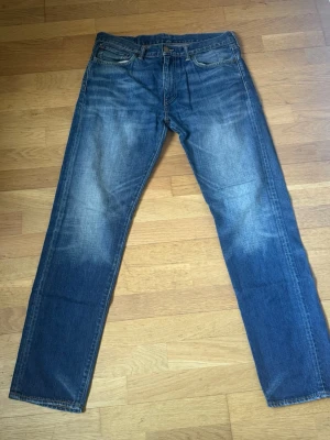 Levis 508 Jeans - Klassiska blå jeans från Levi's med rak passform och fem fickor. Jeansen har en snygg tvättad look med slitningar på låren och knäna. Tillverkade i slitstark denim som ger en tidlös och avslappnad stil. W32 L32.