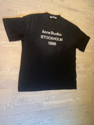 Svart Acne Studios t-shirt - Säljer en svart t-shirt från Acne Studios med vit text på bröstet där det står 'Acne Studios STOCKHOLM 1996'. Storlek är L och den är helt ny. Priset kan diskuteras och skickar inom 24 Tim ☺️💨