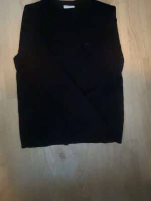 Svart stickad tröja Lindbergh - Klassisk svart stickad tröja från Lindbergh i slim fit-modell. Tröjan har rund halsringning och långa ärmar, perfekt för lager på lager. Enkel och stilren design som passar till det mesta.