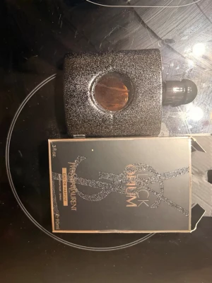 Yves Saint Laurent Black Opium parfym - Black Opium från Yves Saint Laurent är en ikonisk parfym i en svart, glittrig flaska med rundt fönster i mitten. Flaskan har en elegant och modern design med matchande svart kork. Förpackningen är svart med glittriga detaljer och guldtext. Säljs med kvitto