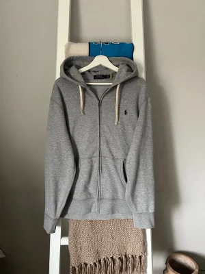 Grå hoodie från Polo Ralph Lauren - Snygg grå zhoodie från Polo Ralph Lauren. Finns QR kod som kan skannas för verifiera äkthet.
