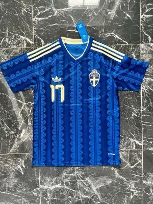 Blå Sverige fotbollströja Adidas - Säljer en blå Sverige fotbollströja från Adidas med retroinspirerat mönster, gula detaljer och nummer 17 på bröstet. Tröjan har korta ärmar, rund hals och tre gula ränder på axlarna. Perfekt för dig som vill sticka ut på match eller träning.