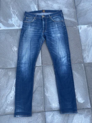 Lee jeans  - Tja! Säljer dessa SJUKT Snygga blå slim fit jeans från Lee med den snyggaste faden jag skådat och slitna detaljer framtill och baktill. Jeansen har en mellanblå tvätt med ljusare partier och kontrastsömmar. Tillverkade i denim med Lee lapp bak i midjan. Modell Luke storlek 31/32! 10/10 skick! OTROLIGT SNYGGA JEANS🤩hör av dig vid mer frågor eller funderingar🕺mvh Ga😁