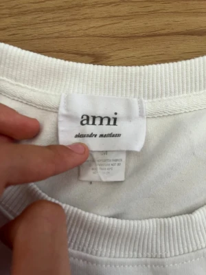 Vit t-shirt från Ami Alexandre Mattiussi - Klassisk vit t-shirt från Ami Alexandre Mattiussi. Tillverkad i mjuk bomull med rund halsringning och enkel design. Perfekt basplagg för en clean och stilren look.