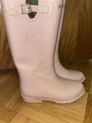  gummistövlar  Tretorn - Säljer ett par ljusrosa höga gummistövlar från Tretorn med justerbart spänne upptill. Klassisk design med grov sula för bra grepp och Tretorn-logga framtill. Perfekta för regniga dagar och festivaler. ”Fläckar ” därmed billiga priset men väldigt sköna och fina. 