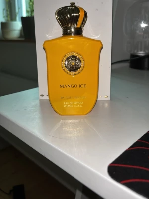 Mango Ice parfym från gulf orchid - Mango Ice Eau de Parfum från gulf orchid i en cool, klargul flaska med guldfärgad kronformad kork och ett lejonemblem framtill. Flaskan rymmer 100 ml och har en lyxig, unik design som verkligen sticker ut i badrumshyllan. HELT NY TESTAT ETT SPRUT. LUTAR MER ÅT FEMENINA HÅLLET PERFEKT FÖR EN TJEJ DOM VILL LUKTA MANGO BOMB!