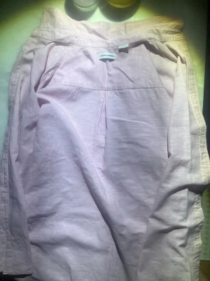 Ljusrosa linneskjorta Jack & Jones - Ljusrosa skjorta från Jack & Jones i svalt linnematerial. Skjortan har klassisk krage och avslappnad passform, perfekt för en enkel och clean stil. Passar dig som gillar ljusa färger och bekväma plagg. Använd fåtal gånger för liten på mig.