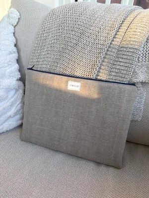 Beige datorfodral från Emelo i stentvättat tyg - Stilren beige fodral från Emelo med mörkblå dragkedja och ljus insida. Perfekt för att organisera laptopen i väskan. Enkel och modern design med diskret logotyp framtill. Passar laptop med maxmått 30x23cm