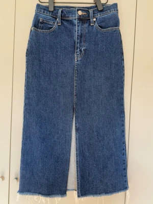 Uniqlo jeanskjol midi W24 / XS 💙 - Snygg jeanskjol med hög midja, slits framtill och rå nederkant ✨ Rak, figurnära modell med stretch.  🏷️ Storlek: W24 / XS (EU 32) 📏 Midja: ca 34 cm plant 📏 Längd: ca 56 cm 🧵 98% bomull, 2% elastan
