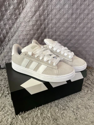 Gråa Adidas Skor - Tjenare. Snygga gråa adidas grand court alpha 00s i storlek 42. Till både killar och tjejer och passar de flesta stilarna. Använda 2 gånger så de är i helt nytt skick. Skokartongen medföljer i köpet. 