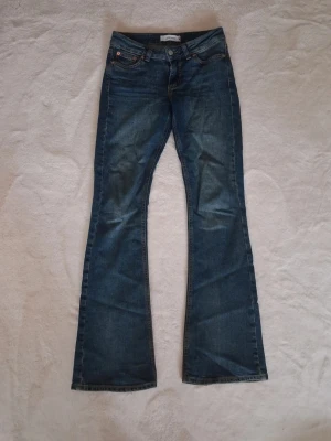 Jeans - Snygga blå bootcut jeans från Junkyard med klassisk femficksmodell och coola kontrastsömmar på bakfickorna. Jeansen har normal midja och utsvängda ben, perfekta för en retroinspirerad look. Tillverkade i slitstarkt denimtyg.