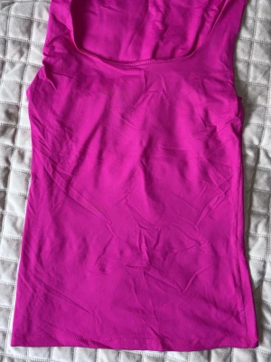 Rosa ärmlös topp från Zara - Snygg och enkel rosa ärmlös topp från Zara. Modellen är figurnära med rund halsringning och tillverkad i ett mjukt, stretchigt material. Perfekt att styla med jeans eller kjol för en trendig look.