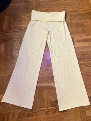 Ljusgula yogabyxor med vida ben - Säljer ett par ljusgula baggy mjukisbyxor från Gina Tricot. Byxorna har en elastisk midja och vida ben för en avslappnad look. Tillverkade i mjukt och stretchigt material som passar perfekt för dagar när man vill ha något avslappnat men ändå snyggt❣️Passar jättebra till crop tops eller hoodies. Jag säljer dem eftersom jag köpte fel storlek, och därför kan jag inte visa dem på mig. Har som sagt bara tagit av prislappen och testat dem en gång ❣️