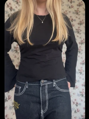 Svart långärmad topp med knyt - Trendig svart långärmad topp med öppen rygg och knyt i sidan. Toppen har en slim passform och är perfekt för dig som vill ha en stilren men ändå unik look ❣️Är använd ett fåtal gånger men har inga skador. 💕