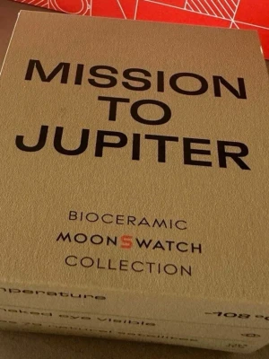 Swatch MoonSwatch Mission to Jupiter - Swatch MoonSwatch Mission to Jupiter från Bioceramic-kollektionen. Klockan har en beige boett, vit urtavla och svarta detaljer. Kronograf-funktion och sportig design. Kommer i originalförpackning med manual.
