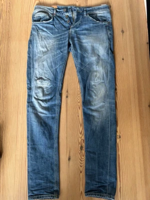 Dondup jeans  - Säljer ett par blå dondup jeans med snyggt slitna detaljer. Storlek 33/32