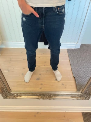 Mörkblå Levis 501 slitningar - Säljer dessa riktigt feta och snygga Levis 501 jeansen. De har riktigt snygga slitningar och fades på framsidan. Modellen på bilden är 183. Storlek 28/30