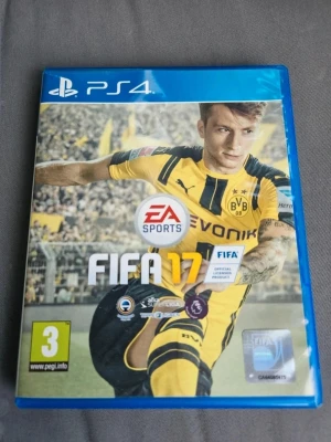 FIFA 17 till PS4 - FIFA 17 till PlayStation 4 med blå plastfodral. Omslaget visar en fotbollsspelare i gul och svart matchtröja från Borussia Dortmund. Spelet är ett fotbollsspel med officiella ligor och lag, och har PEGI 3-märkning. Perfekt för dig som gillar sportspel och fotboll.