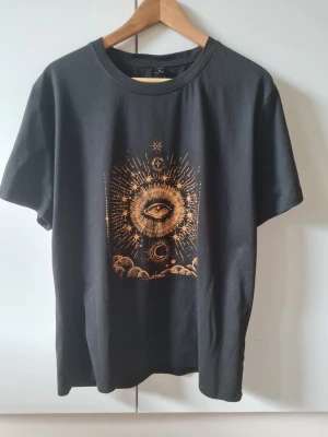 Svart öga av försynens tarot T-shirt strl M - Överdimensionerad t-shirt med tarotkortstryck. Strechigt material. Information om material är urtvättad. Storlek M.