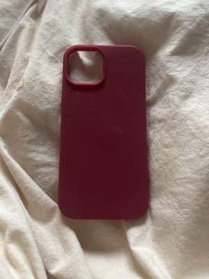 Vinrött mobilskal i silikon till iphone 15 - Snyggt vinrött mobilskal i mjukt silikonmaterial. Skalets design är enkel och stilren med rundade hörn och ett stort kamerahål. Passar perfekt för dig som vill ha ett skal som känns modernt och skyddar mobilen utan att vara för klumpigt.