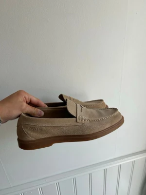 Beige mocka loafers från Novita -  beige loafers i mocka från Novita med bruna gummisulor. 